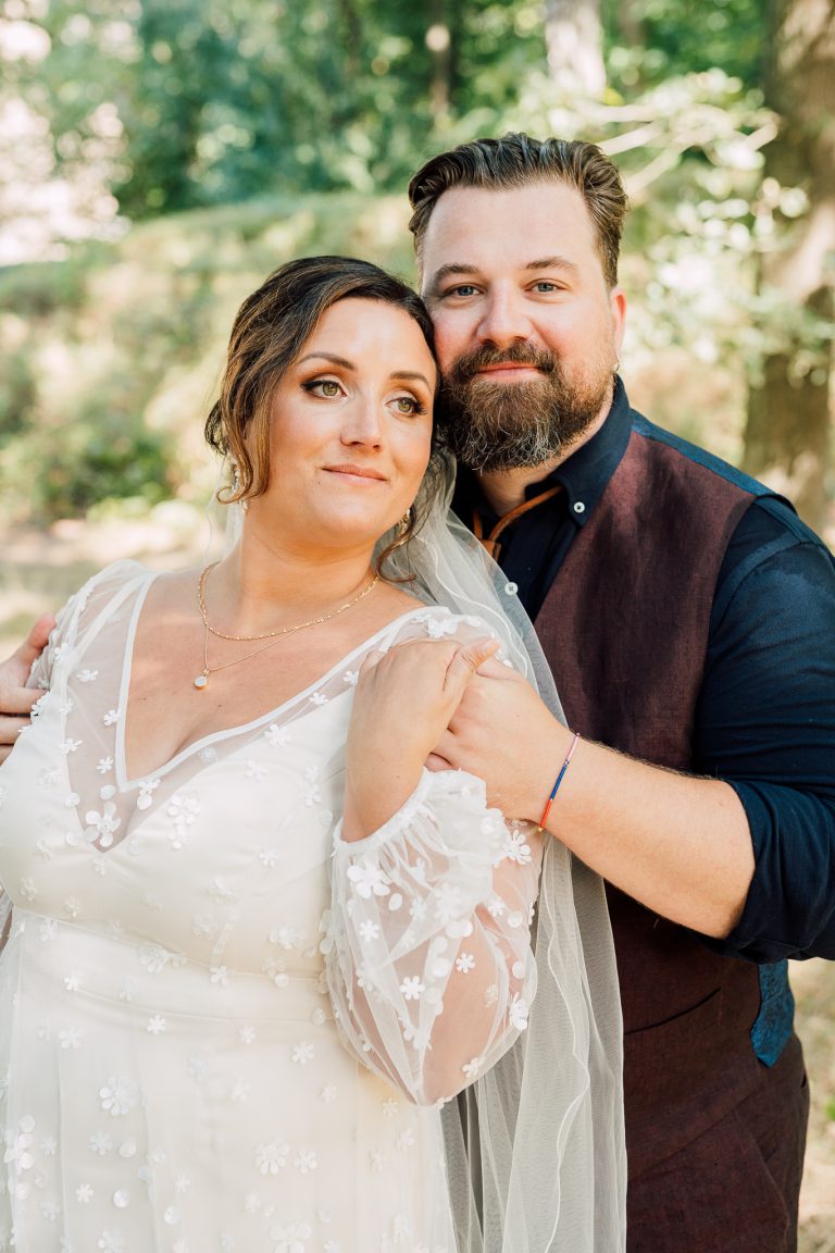 Dit bruidspaar houdt elkaar liefdevol vast in de natuur. De bruidsfotograaf uit Arnhem heeft een tijdloze stijl.