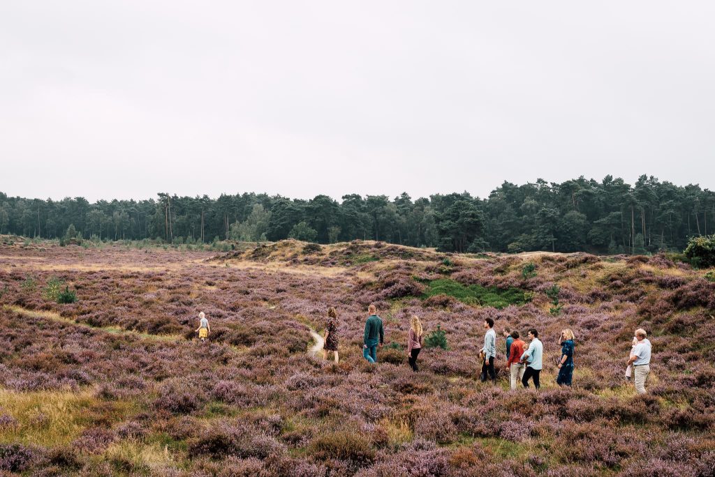 een grote familie tijdens de familie fotoshoot wandelend achter elkaar aan in de natuur